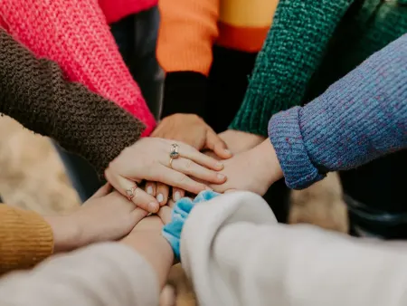 A group of people stacking their hands together in the middle of a circle